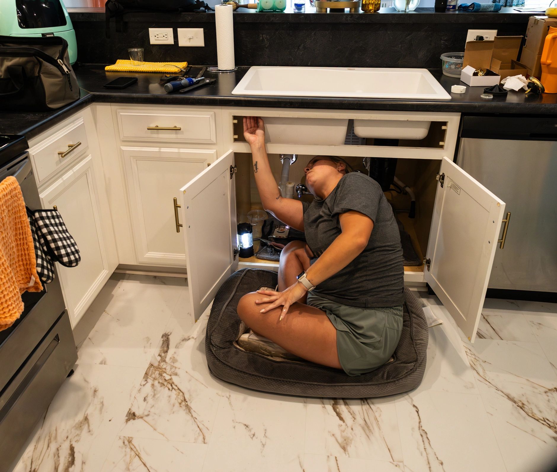 Technician carrying out plumbing repair beneath a sink